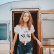 Woman walking out of an RV in a white shirt and jeans.