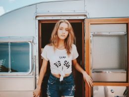 Woman walking out of an RV in a white shirt and jeans.
