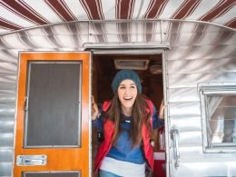 A happy woman poking her head out of a camper.