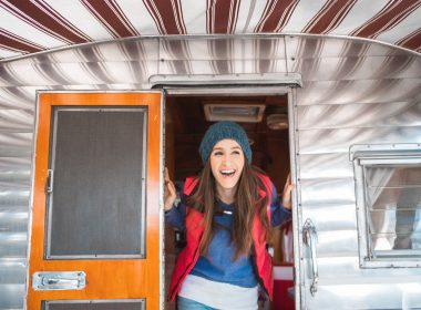 A happy woman poking her head out of a camper.