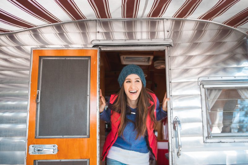 A happy woman poking her head out of a camper.