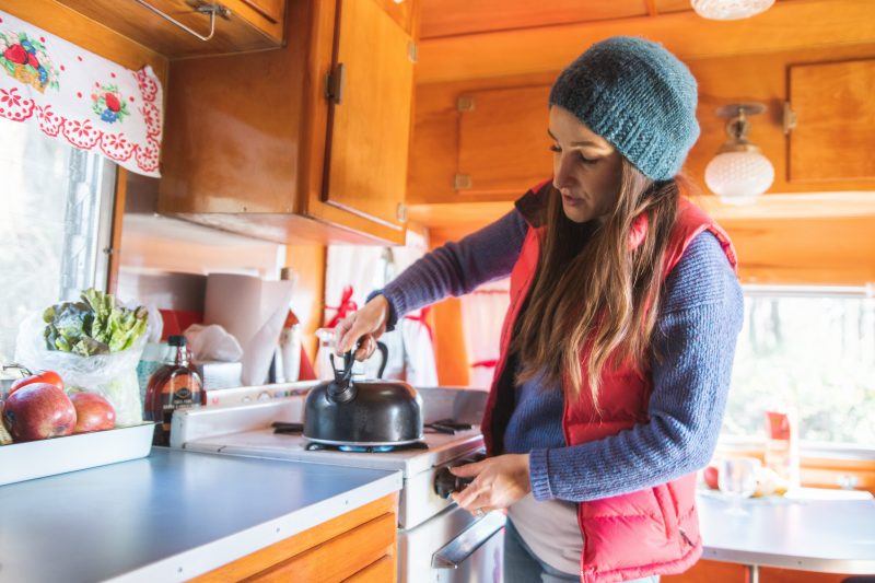 Woman preparing tea in her camper.