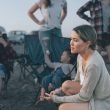 Sad woman looks away as friends stand in a put off manner behind her at a campground.