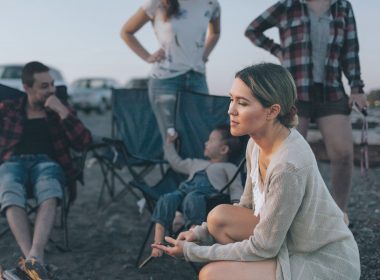 Sad woman looks away as friends stand in a put off manner behind her at a campground.