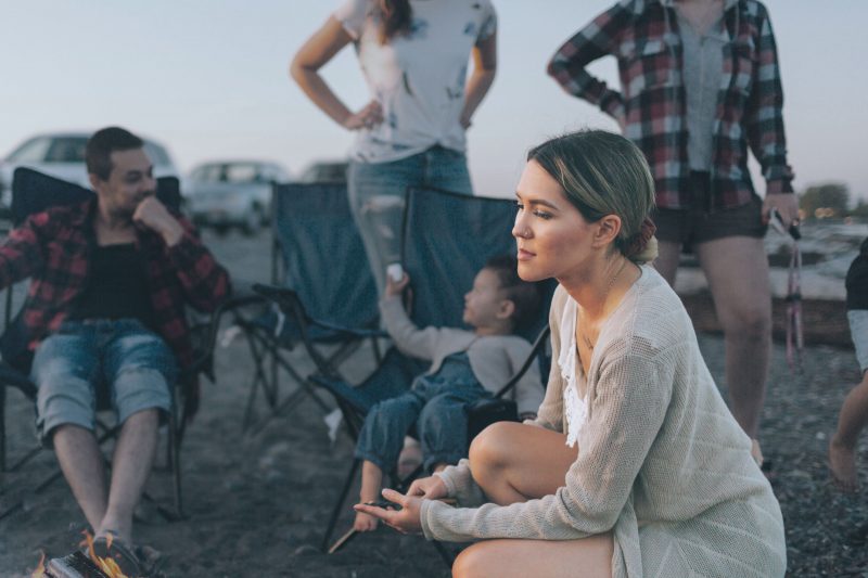 Sad woman looks away as friends stand in a put off manner behind her at a campground.