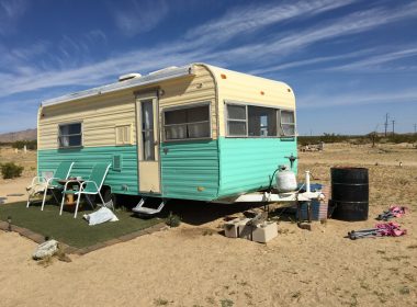Vintage cream and teal travel trailer parked in the desert.