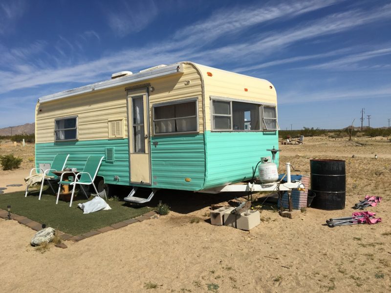 Vintage cream and teal travel trailer parked in the desert.