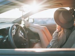 A woman sitting in the passenger seat of a car at golden hour.