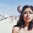 Topless woman wearing horns in the desert where RVs have gathered for a festival.