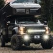 The EarthRoamer LTS overlander adventures through a remote mountain setting heading towards the camera with its headlights on.