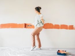 Woman dancing with her earbuds in while painting a wall.