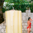 A woman shower outside a campground station in her red bathing suit.