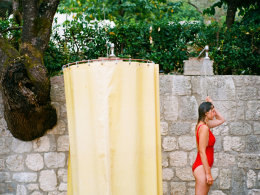 A woman shower outside a campground station in her red bathing suit.