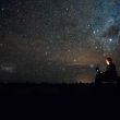 Sitting outside on a laptop using the internet underneath starts and satellites in the night sky