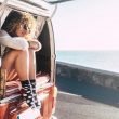 A woman in shorts and cute socks sitting with her legs out the back of her camper van enjoying van life.