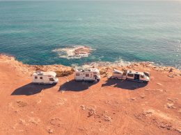 Two motorhomes and a camper van are parked along a cliff next to the the ocean coast