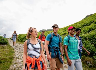 A group of friends hiking on a crowded trail in the mountains.