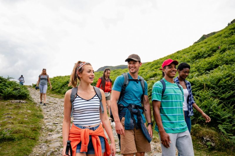 A group of friends hiking on a crowded trail in the mountains.