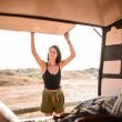 A woman opens the back door to her camper van, a small Class B motohorme