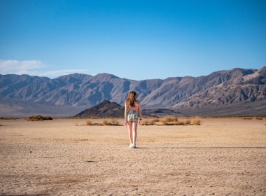 A woman from behind walking through the vast desert in Death Valley National Park
