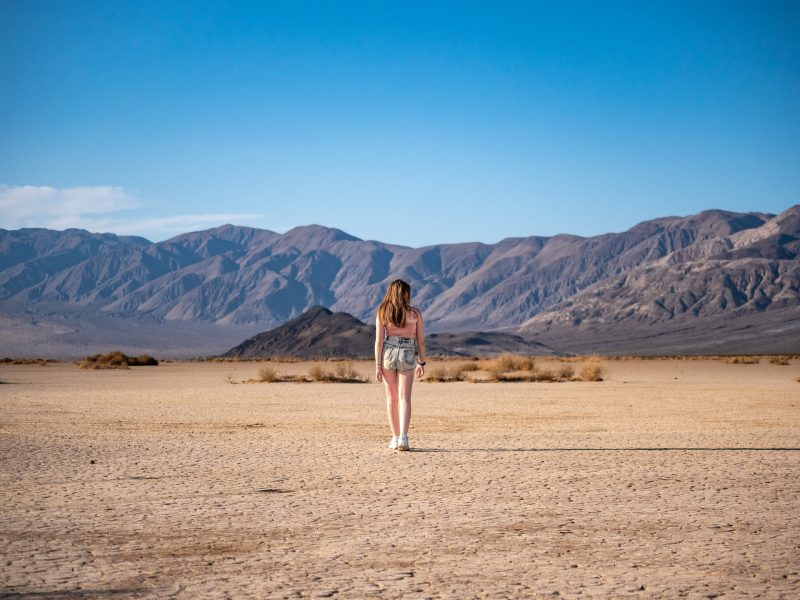 A woman from behind walking through the vast desert in Death Valley National Park