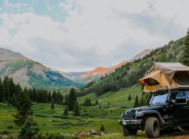 A Jeep with a topper tent in the mountain wilderness.