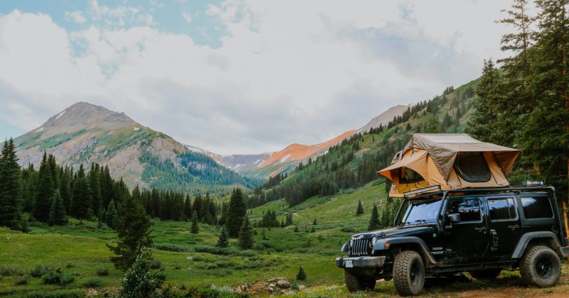A Jeep with a topper tent in the mountain wilderness.