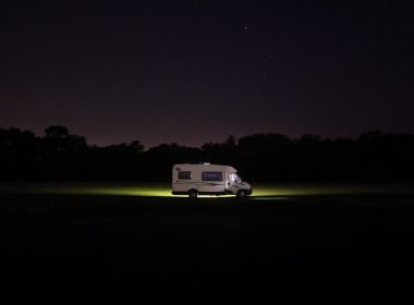 An RV driving down the road at night looking for overnight parking.