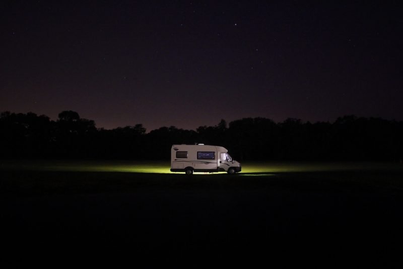 An RV driving down the road at night looking for overnight parking.
