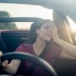 A tired driver leans her head in her hand as she embarks on a long road trip
