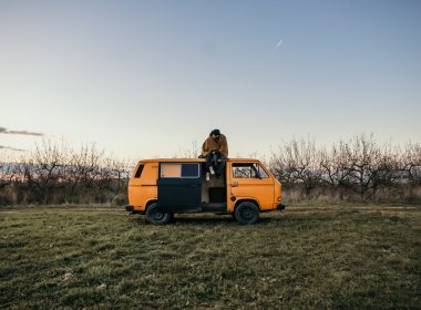 A couple cuddles in a blanket on top of their campervan