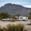 A Airstream travel trailer and truck parked in the dessert with solar panels.