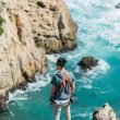 A man overlooks the waves crashing below him along the rocky coastline in Big Sur.