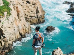 A man overlooks the waves crashing below him along the rocky coastline in Big Sur.