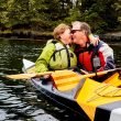 A mature couple kayaking together and embracing.