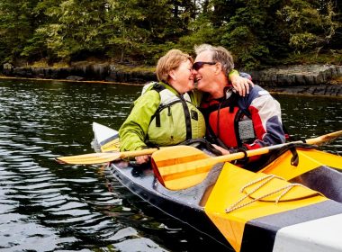 A mature couple kayaking together and embracing.