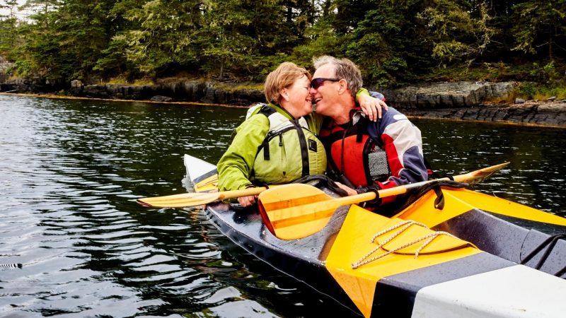 A mature couple kayaking together and embracing.
