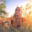 A woman crouches in the bushes in the woods.