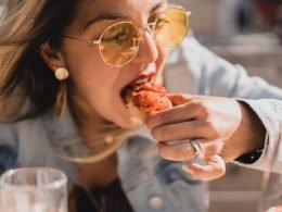A woman leans over her plate to eat yummy food with her hands.