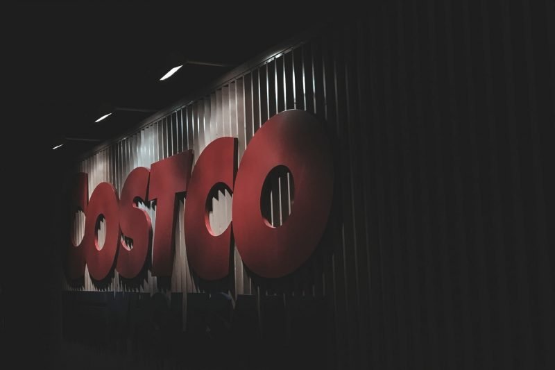 A dimly lit Costco sign on the side of the warehouse at night.