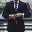 A business man wearing a suit from the neck down.