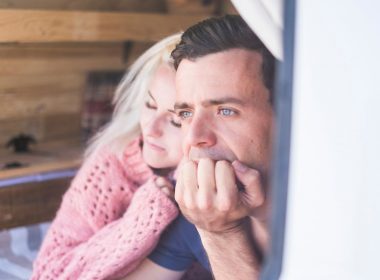A couple lays in the back of their campervan in thought.