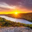 The sun sets over the fall colors and a lake in the Porcupine Mountains.