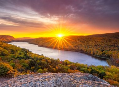 The sun sets over the fall colors and a lake in the Porcupine Mountains.