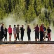 A crowded boardwalk in Yellowstone National Park is filled with tourists.