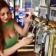 A sexy woman pours beer from a tap behind a bar.