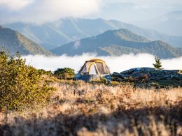 Tent camping in the mountains as the gof rolls over the slopes in the morning.
