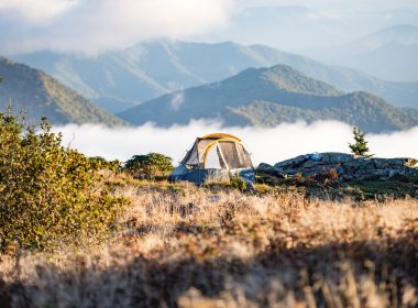 Tent camping in the mountains as the gof rolls over the slopes in the morning.