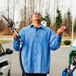 A man holds up the gas pump in frustration of the price of fuel.