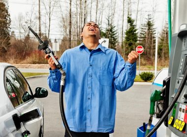 A man holds up the gas pump in frustration of the price of fuel.